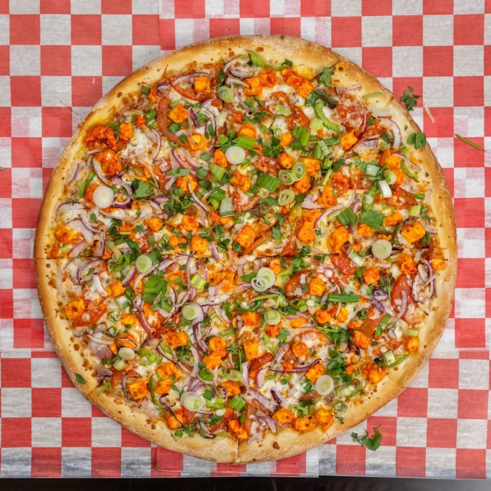 Garlex Pizza & Ribs' chicken tikka pizza, topped with red onions, green onions, and cilantro.