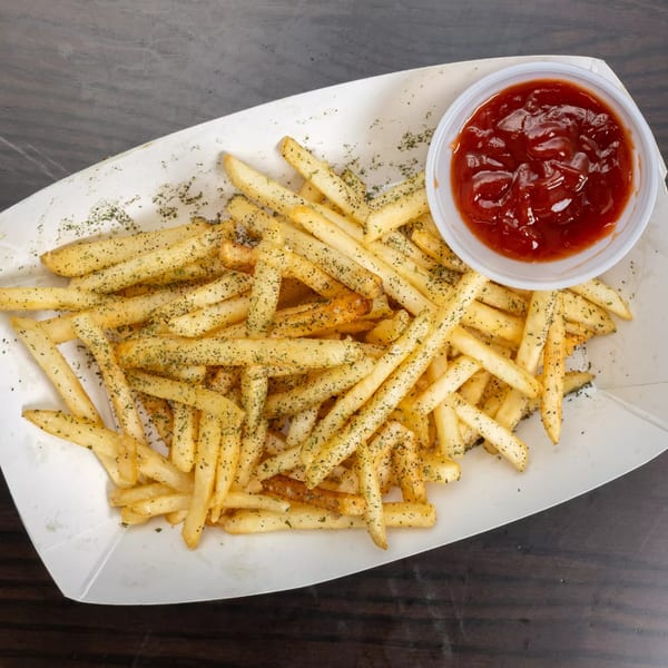 Garlex Pizza & Ribs' seasoned fries in a white tray with a side of ketchup.