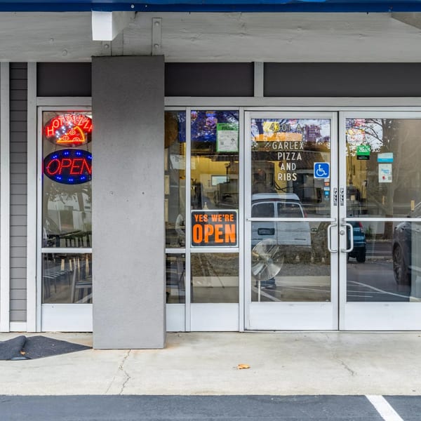 Garlex Pizza and Ribs storefront with "Hot Pizza" and "Open" neon signs, and a "Yes We're Open" sign.