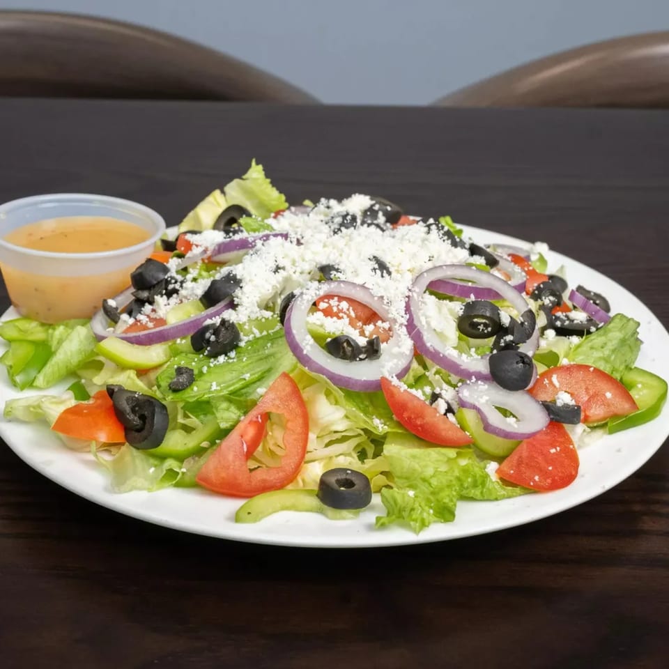 A fresh Garlex Italian salad with lettuce, tomatoes, olives, red onions, and feta cheese.